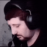 a man with a beard is wearing headphones and a microphone in a dark room .