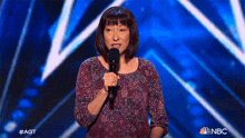 a woman is holding a microphone on a stage with a nbc logo in the corner