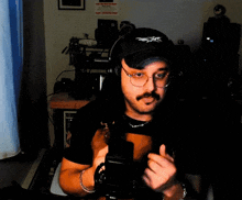 a man giving a thumbs up while wearing headphones and a hat that says x on it
