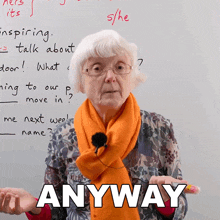 an elderly woman wearing an orange scarf stands in front of a whiteboard with the words anyway written on it