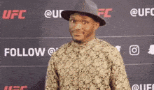 a man wearing a hat and a shirt is standing in front of a sign that says follow