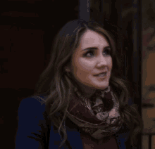 a woman wearing a scarf and a blue jacket looks up