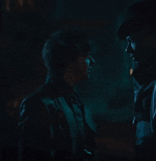a man in a hat is talking to a woman in a dark room