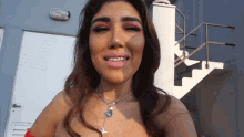 a woman wearing a necklace with a cross on it is smiling