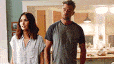 a man and a woman are standing next to each other in a kitchen and holding hands .