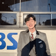 a man in a suit and tie is standing in front of a bus .