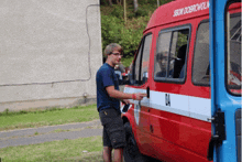 a man standing next to a red van that says bom dobrovoln on the side