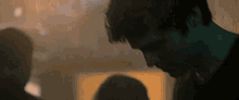 a close up of a man 's face in a dark room looking down .