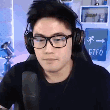a man wearing headphones and glasses is sitting in front of a gtfo sign