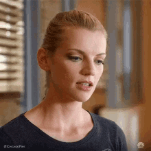 a close up of a woman 's face with a ponytail and a black shirt .