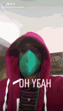 a man wearing a pink hoodie and a green mask says " oh yeah "