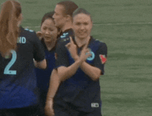 a group of female soccer players are standing on a field giving each other high fives .