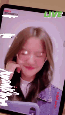 a girl wearing glasses and a denim jacket is on a tablet with the word live above her