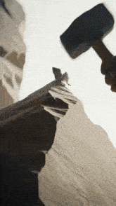 a person is holding a hammer over a rock