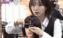 a woman in a white shirt is cutting a mannequin 's hair with scissors in a hair salon