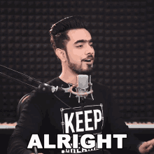 a man singing into a microphone wearing a shirt that says " keep alright "