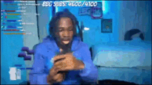 a man in a blue hoodie is sitting on a couch in front of a blue wall .