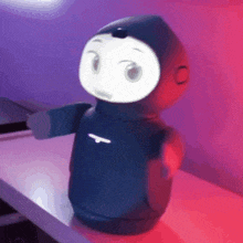 a black robot is sitting on a table with purple lights behind it .