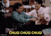 two men are sitting on a couch and laughing .