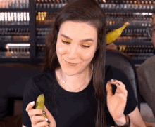 a woman in a black shirt is holding a banana