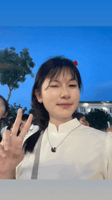 a girl wearing a white shirt and a necklace with the letter s on it