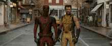deadpool and wolverine are standing next to each other on the street