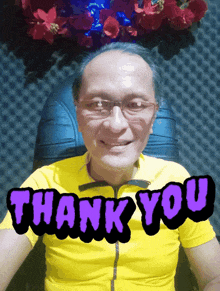 a man wearing glasses and a yellow shirt says thank you in purple letters