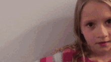 a little girl in a pink and white striped shirt looks at the camera