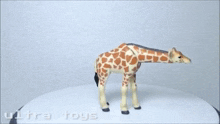 a giraffe figurine is standing on a white surface with the words ultra toys written on it