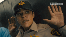 a woman in a los angeles county sheriff 's uniform holds her hands up