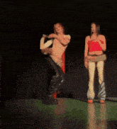 a man and a woman are dancing on a stage and the woman is wearing a red top