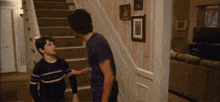 two boys are standing on a set of stairs and one of them is wearing a striped shirt
