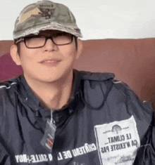 a man wearing glasses and a hat has a tag on his jacket that says ' tamu '