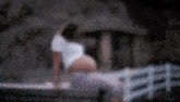 a pregnant woman is sitting on a bench in front of a bridge .