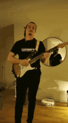 a man playing a guitar in front of a mirror that says ' midtown ' on it