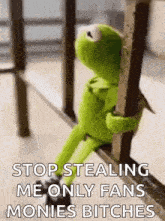 kermit the frog is sitting on a railing and holding onto a railing while holding a pole .