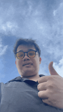a man wearing glasses and giving a thumbs up