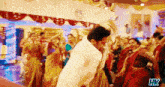 a man in a white shirt is dancing in front of a crowd with the letters hk above him