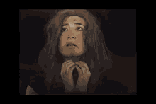 a woman with long hair is making a funny face with her hands .