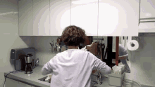 a woman is washing dishes in a kitchen and looking at herself in the mirror .