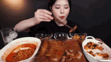 a woman is sitting at a table eating a variety of food with chopsticks