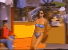a woman in a bikini is standing in front of a yellow box