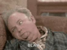 a man is laying on a couch sticking his tongue out and making a funny face .