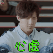a young man is sitting in a classroom with chinese writing on his face .