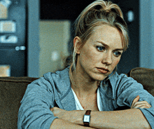 a woman sitting on a couch with her arms crossed wearing a watch