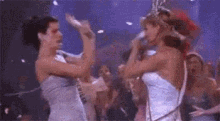 a group of women are dancing on a stage and one of them is wearing a crown .