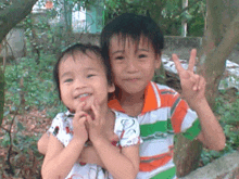 a boy and a girl are posing for a picture and the boy is wearing an orange shirt