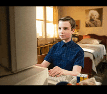 a young boy in a blue shirt is typing on a computer