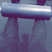 a person is holding a cylinder on their feet