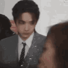 a man in a suit and tie is talking to a woman in a crowd .
